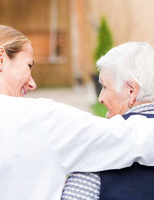 A Grow Care carer with her arm around a client at home