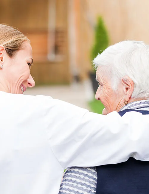 A carer with her arm around a client at home