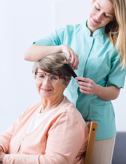 A Grow Care carer helping a client with her hair at home, both smiling